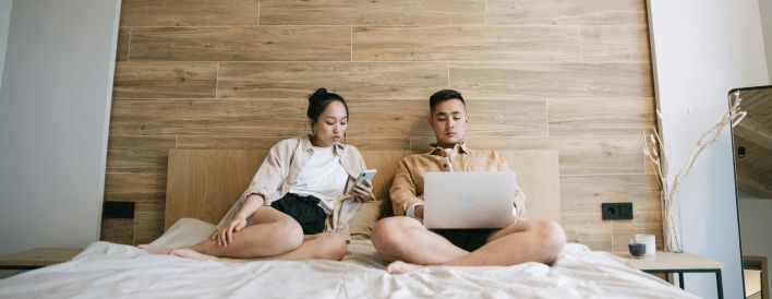 Man and Woman Sitting on Bed While Using Gadgets